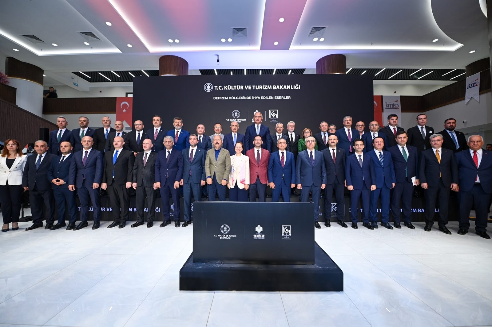 Bakanlık etkinliği sahnesinde resmî heyet toplu poz veriyor.