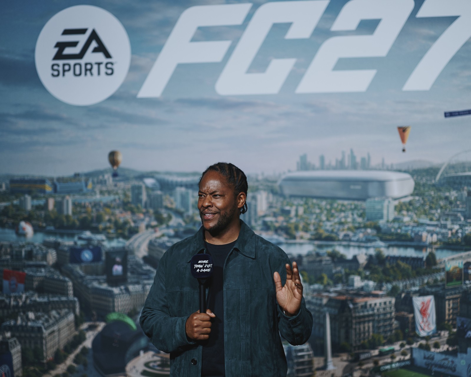 EA SPORTS FC 27 arka perdesi önünde elinde mikrofonla konuşan etkinlik sunucusu
