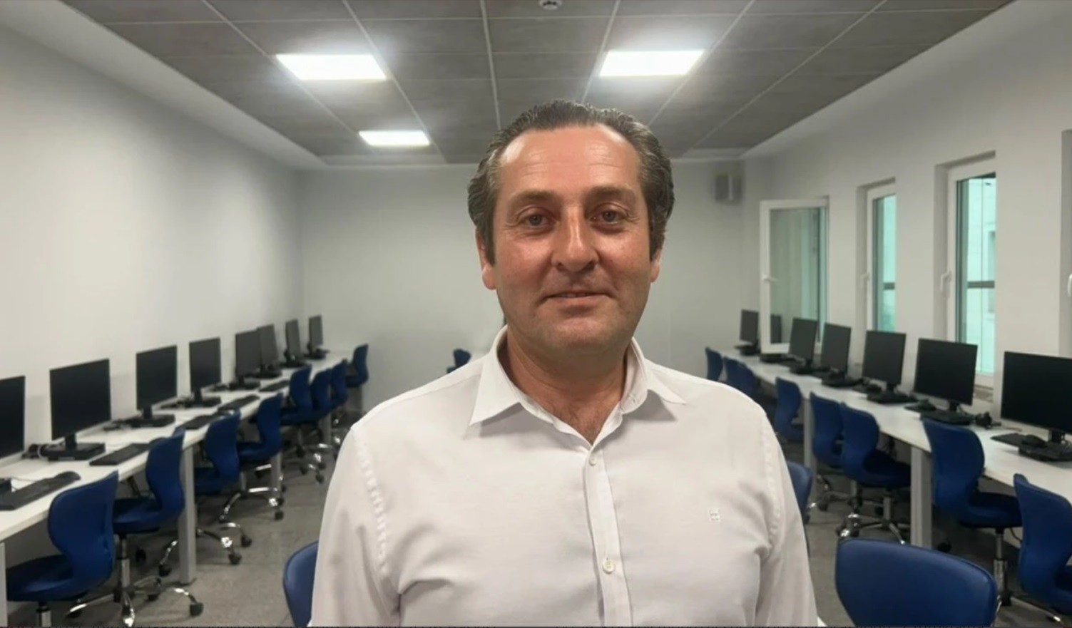 Bilgisayar laboratuvarında beyaz gömlekli yetişkin uzmanın portresi.
